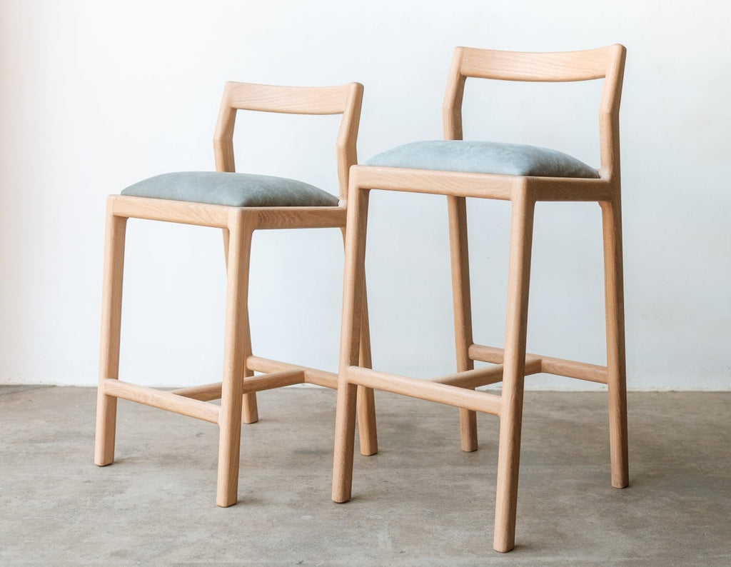 Two wooden bar stools with light blue seats on a gray floor.