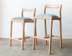 Two wooden bar stools with light blue seats on a gray floor.